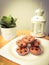 Chocolate chips muffins decorated with tiny tree pot and lamp or lantern on wooden spruce desk with pastel retro filter effect