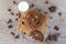 Chocolate cookies with hazelnuts, white chocolate and dark chocolate on parchment and glass of milk, wooden background, flat lay