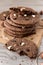 Chocolate cookies with hazelnuts, white chocolate and dark chocolate on parchment, wooden background, vertical
