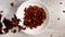 Chocolate cornflakes are flying from above into a white dish in slow motion