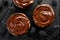 Chocolate-covered small cheesecakes  on a cooling tray on dark background,  top view, close-up.