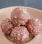 Chocolate & Crushed Almond Crispy Balls on a Light Brown Serving Plate and in Natural Light