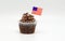 Chocolate cupcake with an American flag toothpick in it isolated on white