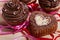 Chocolate cupcakes with chocolate cream and cupcake in the shape of heart, decorated with ribbon, on a wooden background.