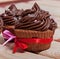 Chocolate cupcakes with chocolate cream, decorated with ribbon, on a wooden background with the inscription love.