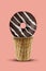 Chocolate donut with white icing in sweet wafer cup against pink background. Food, treats and unhealthy nutrition. Close