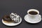 Chocolate donuts and coffee. Two beautiful tasty donuts on a saucer and a cup of aromatic hot coffee