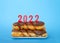 Chocolate donuts stacked with 2022 Happy New Year candles on blue