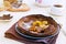 Chocolate Dutch Baby pancake with caramelized bananas on a gray plate on a light concrete background. Selective focus. American