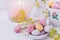 Chocolate Easter eggs in pastel colors in ceramic spoon, burning candle, white napkin