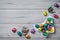 Chocolate Easter eggs wrapped in colorful foil in a butterfly shaped bowl on a wooden background, top view, copy space