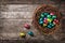 Chocolate easter eggs wrapped in colourful foil in the nest on wooden background, top view