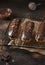 Chocolate eclairs, pieces of chocolate and a bowl with glaze on a dark concrete background.