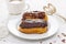 Chocolate eclairs on white dish on wooden background