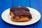 Chocolate eclairs on white dish on wooden background