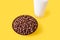 Chocolate flakes in the form of balls in a bowl and a glass of milk on a yellow background