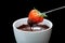 Chocolate fondue on ramekin and fresh and red strawberry on stick