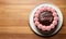 A chocolate frosted cake with pink frosting on a white plate with text word SORRY