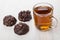 Chocolate glazed cookies with peanuts, transparent cup with tea