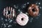 Chocolate and glazed donuts, pink, white, brown on black stone, top view