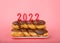 Chocolate glazed twist donuts on rectangular plate with 2022 candles on pink