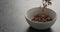 Chocolate granola fall into white bowl on terrazzo surface