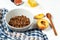 Chocolate granola in a white bowl in a composition with honeycombs, a spoon, figs and peach. Healthy breakfast food. Making