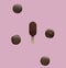 Chocolate ice lolly and french macrons on pink background.