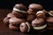 Chocolate macarons of various sizes. Brown background