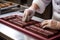 chocolate-maker expertly wrapping finished bars in decorative packaging