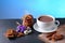 Chocolate milk, hot cup of cocoa, chocolate cookies, almonds, flowers on a shale board on bright blue background, place to copy te