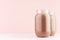 Chocolate milkshake in two stylish jars on white wooden table and pastel light pink wall.