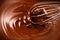 Chocolate. Mixing melted dark chocolate with a whisk. Closeup of liquid hot chocolate swirl