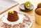 Chocolate Moelleux cake or molten cake, with kiwi fruit, by a bowl with entire kiwi fruit over a wooden background