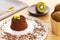 Chocolate Moelleux cake or molten cake with kiwi fruit, by a golden spoon and bowl with entire kiwi fruit over a wooden background