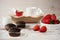 Chocolate muffins, coffee, strawberries, a vase of white flowers. Light wood rustic background