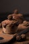 Chocolate muffins, decorated with a small cone on a dark wooden background. Cupcakes are poured with dark chocolate and cocoa powd