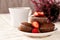 Chocolate muffins with strawberries on a saucer with a white cup of coffee.