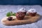 Chocolate muffins on a wooden board, strewed with icing sugar.