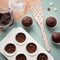 Chocolate muffins on a wooden table with kitchen tools, a jar full of chocolate pieces and hearth-shaped chocolates.
