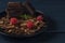 Chocolate pieces with chocolate shavings, mint and raspberry in black plate on dark wooden background