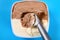 Chocolate plus vanilla ice cream with a spoon and some digged out on blue background