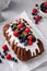 Chocolate pound cake topped with cream cheese glaze and berries