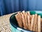 Chocolate rolled wafers stick in green bowl on rattan table with blue curtain background