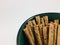 Chocolate rolled wafers stick in green bowl with white background