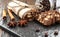 Chocolate salami on a stone slab, cinnamon and star anise sticks lie nearby, coffee beans pour out from a glass jar