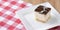 Chocolate souffle with thick chocolate ganache glaze served on a white plate on red plaid background