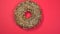 Chocolate sweet donut rotating on a plate. Top view. Red background.