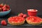 Chocolate tart, tartalette with white chocolate and mascarpone cream, fresh strawberries on top. Large blue bowl full of