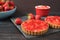 Chocolate tart, tartalette with white chocolate and mascarpone cream, fresh strawberries on top. Large blue bowl full of